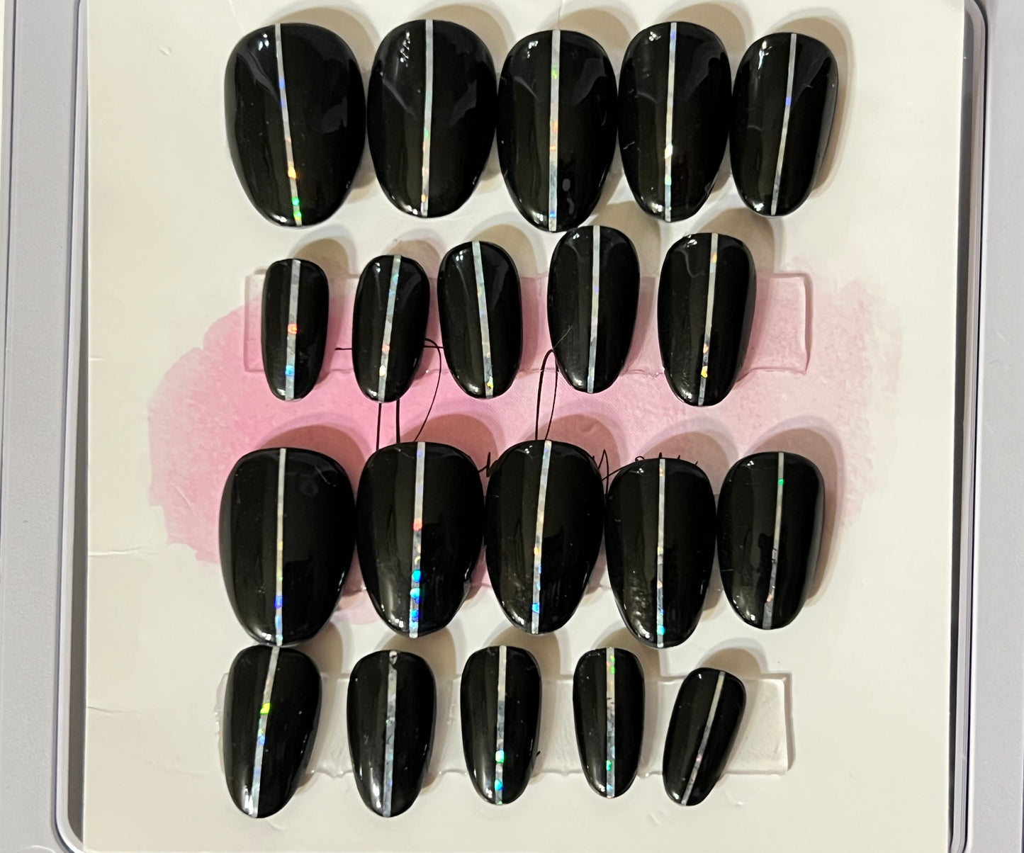 Set of 20 natural short round press-on nails with black gel polish and a pin stripe down the center. 